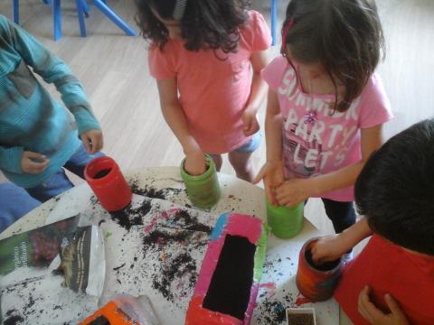 As crianças de CATL a plantar/semear nos recipientes reutilizados.
