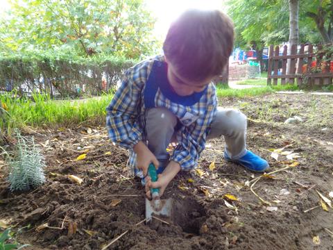 Aluno da sala dos 5 anos a preparar a terra para plantar.