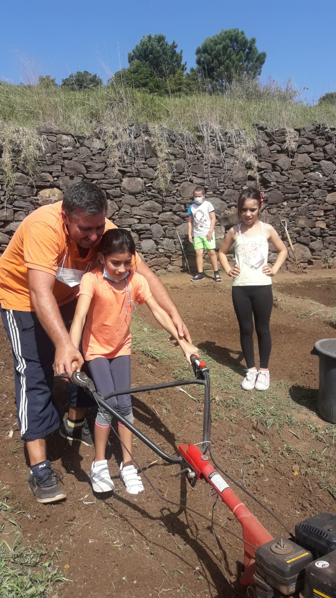 Remexer da terra com ajuda de uma máquina e dos encarregados de educação.