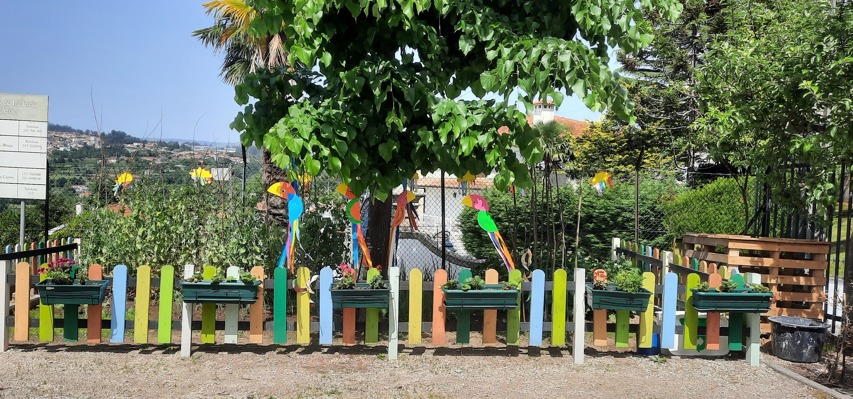 Vista geral. 
A horta como se encontra neste momento, com destaque para o compostor que está situado do lado direito junto da horta. Podemos observar os papagaios, arcos iris e as cobras com o objetivo de espantar os pássaros e decorar  o espaço..