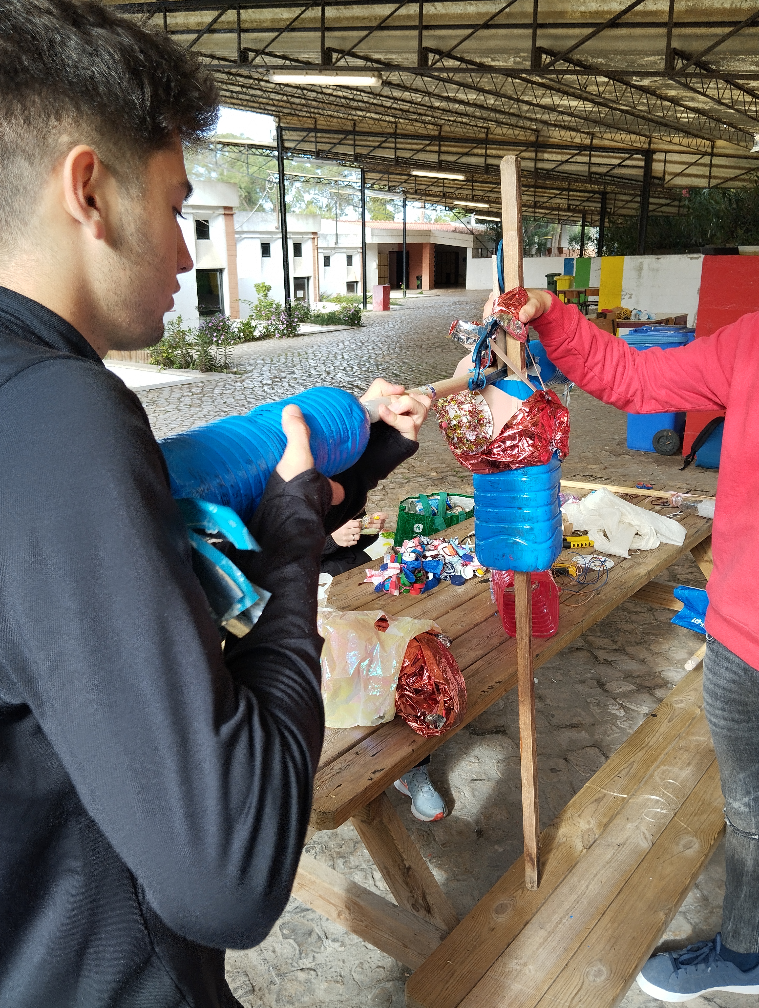 As tarefas foram realizadas com a participação de todos os elementos do grupo. 
Nos braços vão ser penduradas tampinhas e latas de refrigerantes, como fossem um xaile, para se moverem com o vento e fazerem ruído.