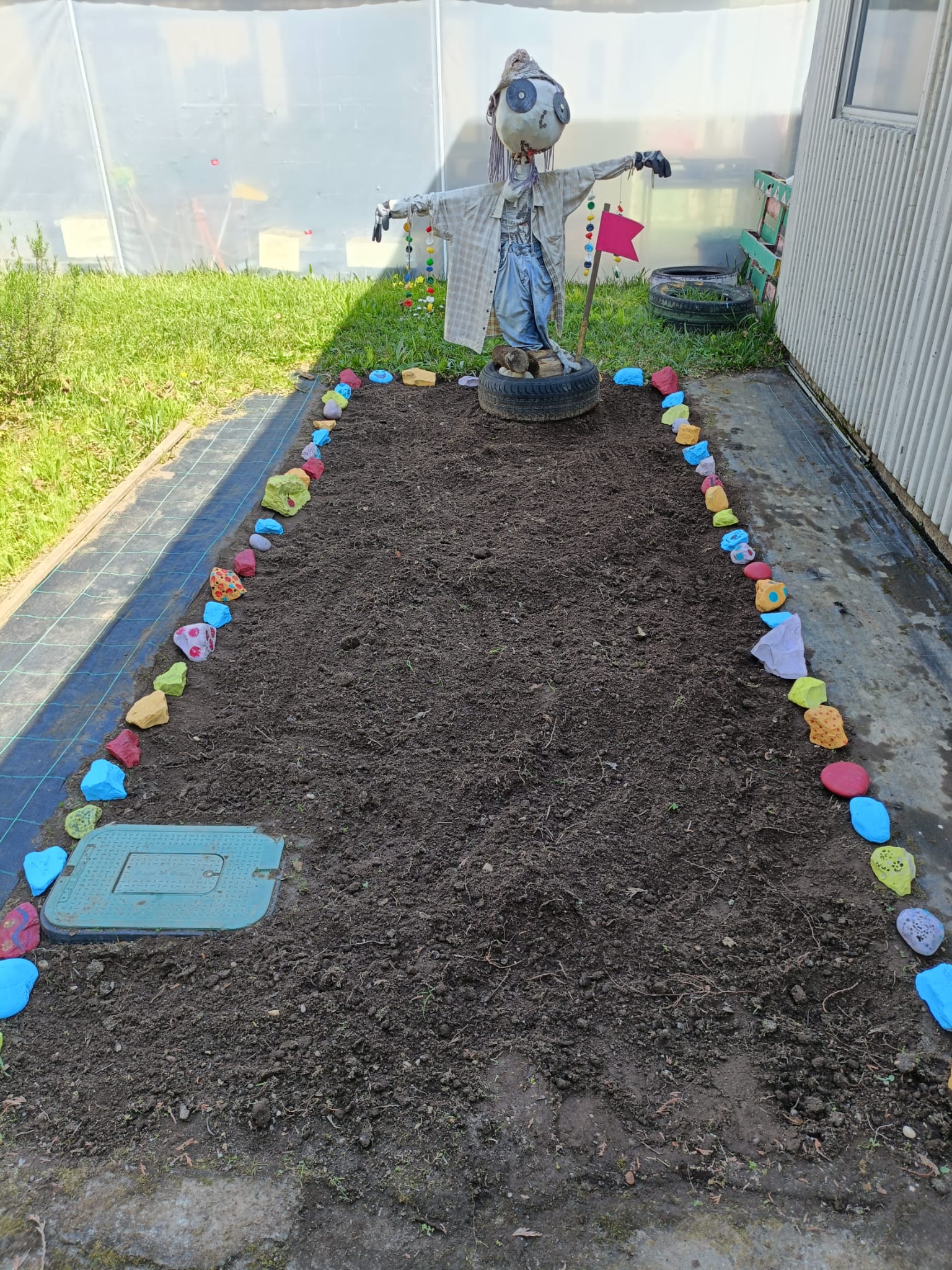 Espaço da horta limpo de ervas invasoras, pronto para a plantação. 
Pedras decoradas pelas crianças para delimitar o espaço da horta.