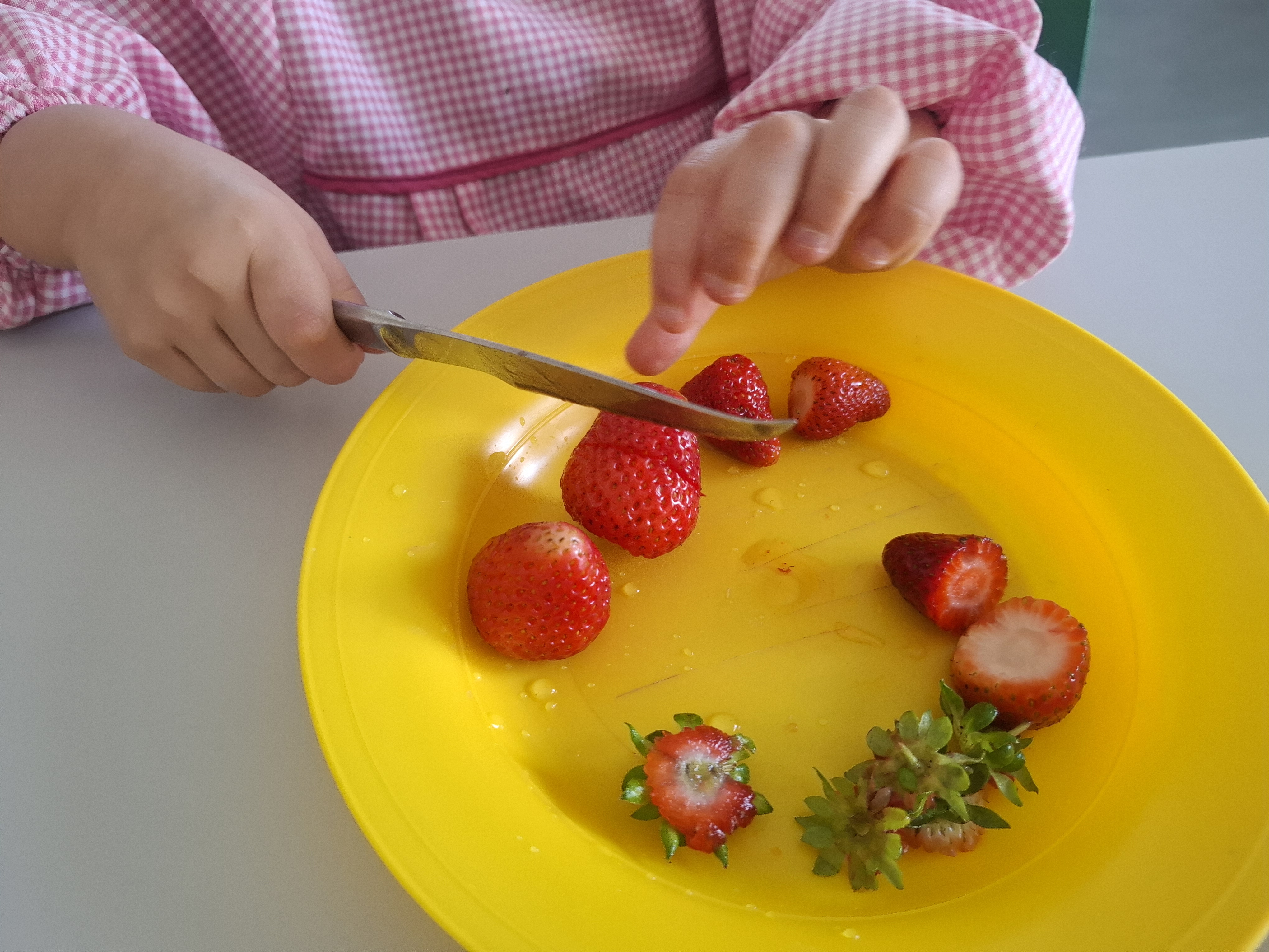O mesmo grupo preparou uma salada, trabalhando a motricidade fina e explorando sensorialmente os morangos colhidos.
