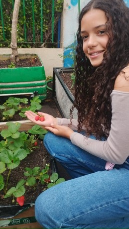 A aluna ficou contente com a colheita de morangos.