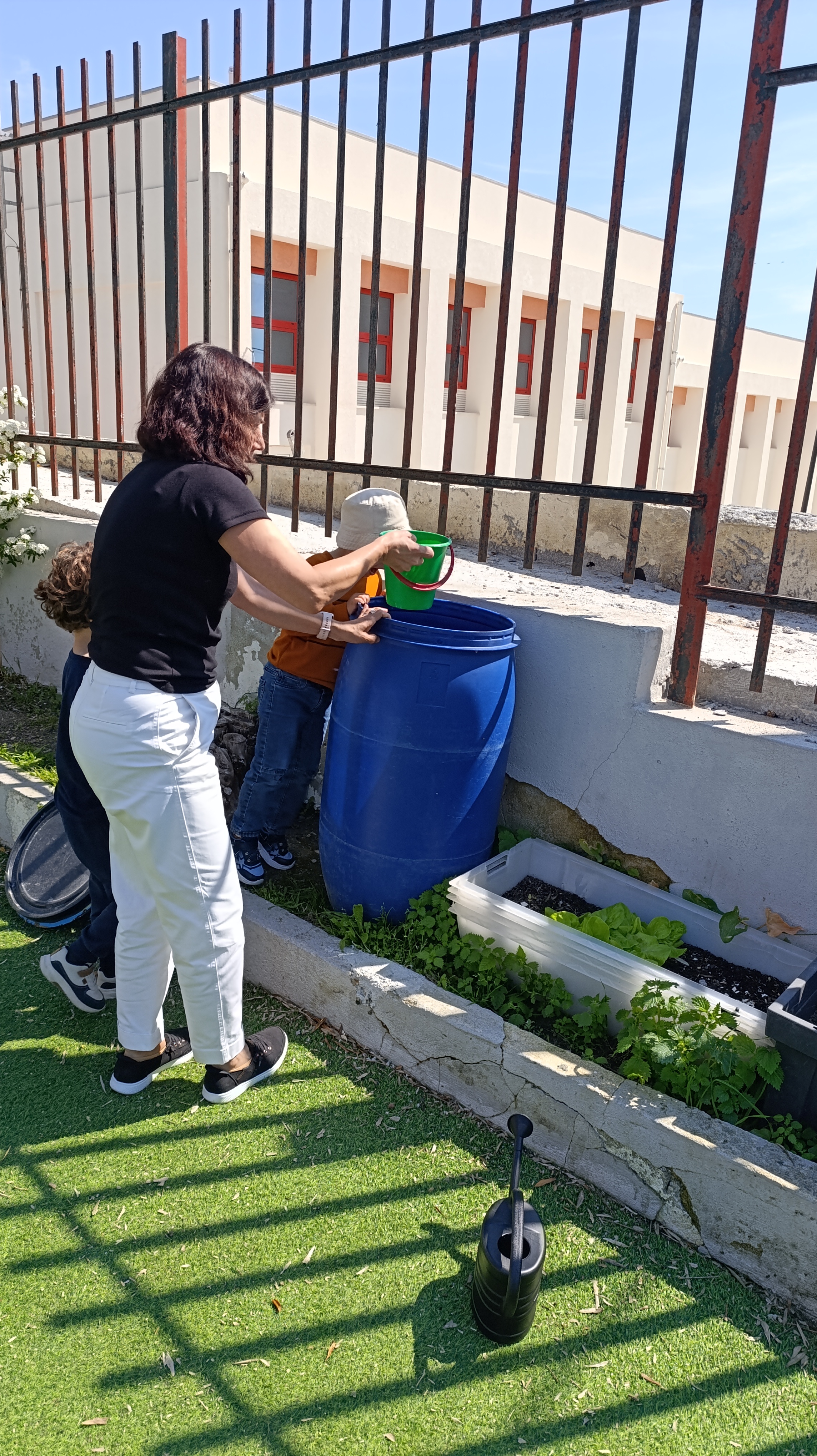 "Rega da horta" - com a água da chuva, acumulada no bidão, as crianças regam a horta.