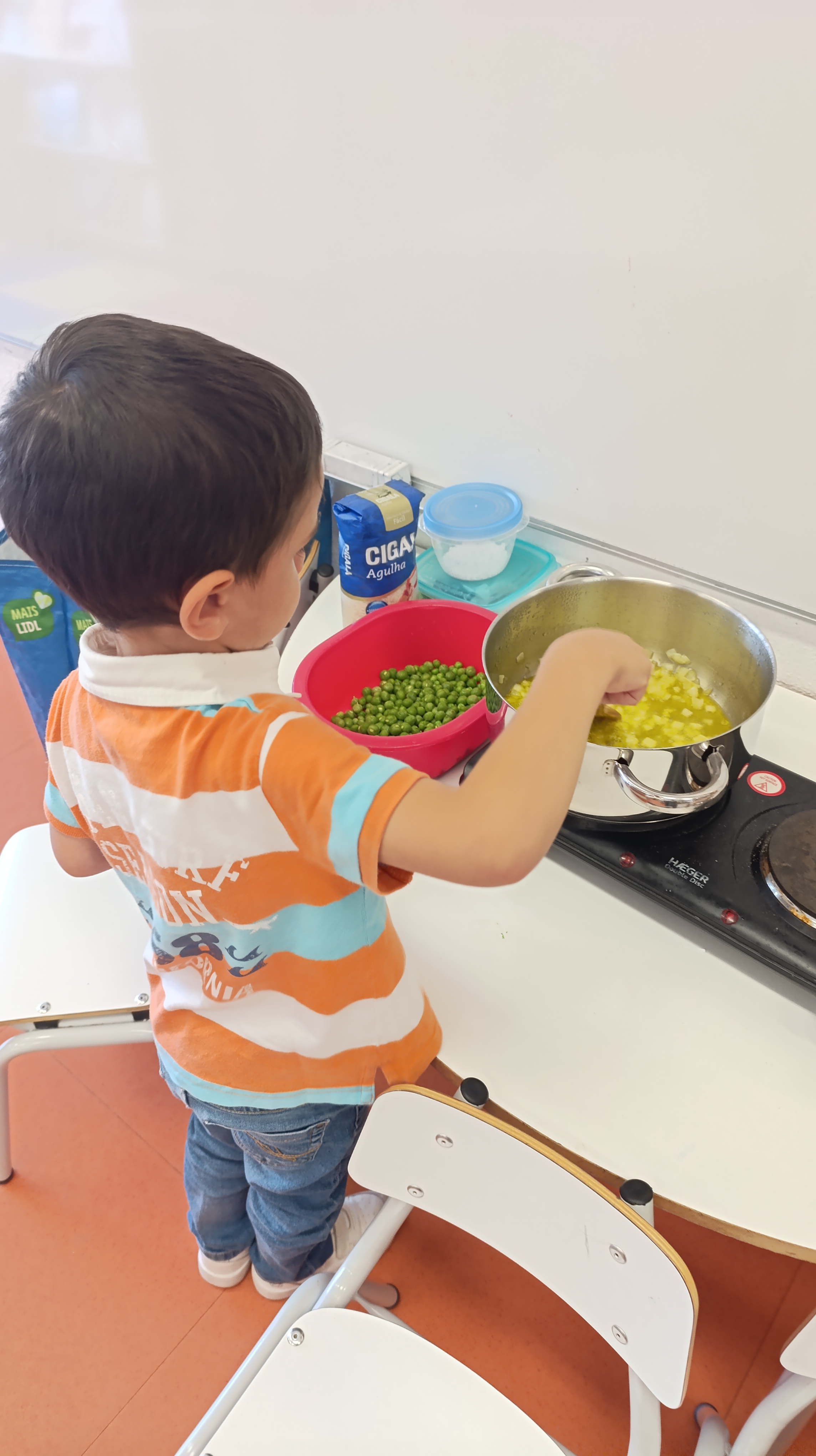 "Receita de arroz de ervilhas" - a criança mexe o refogado para fazer o arroz com as ervilhas